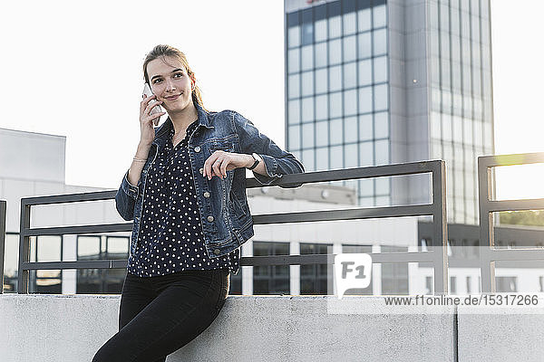 Smiling young woman on cell phone standing on parking deck