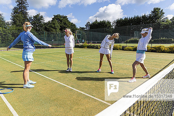 Reife Frauen machen vor dem Tennisspielen Dehnungsübungen