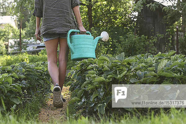 Close-up of woman with watering can walking in garden