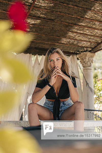 Portrait of a beautiful young woman sitting on a table outdoors
