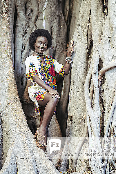 Lächelnde junge Frau posiert in einem Baumstamm