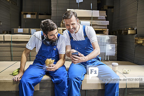 Zwei glückliche Arbeiterinnen telefonieren während der Mittagspause in der Fabrik