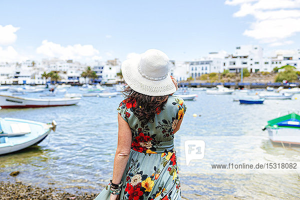 Rückansicht einer Frau mit weißem Sonnenhut im Hafen von Arrecife  Spanien