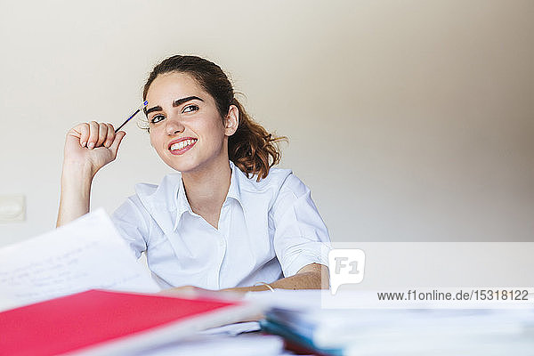 Smiling female student learning at desk at home