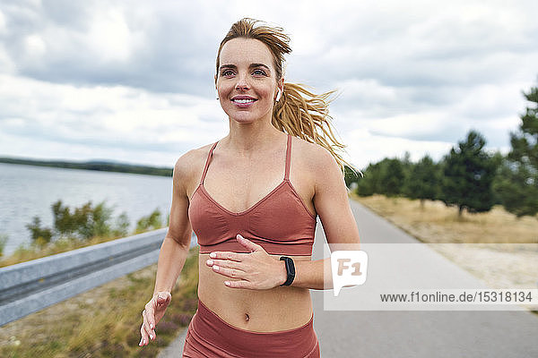 Porträt einer lächelnden athletischen Frau  die im Freien joggt