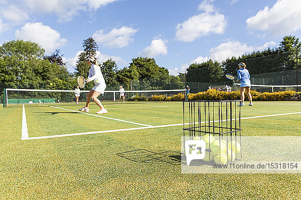 Ältere Frauen spielen Tennis auf Rasen