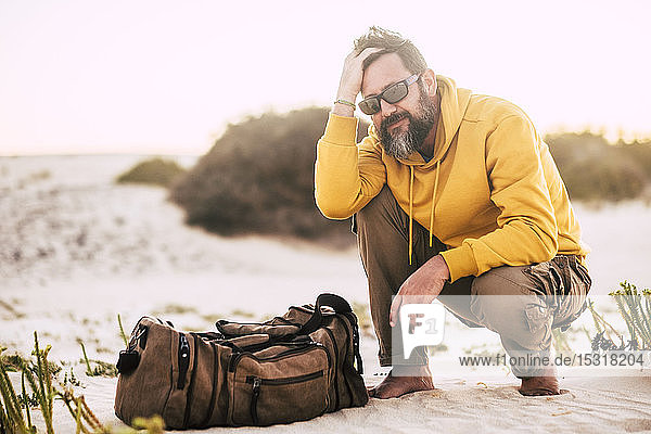 Man with yellow hoodie sweater and brown basket at the beach