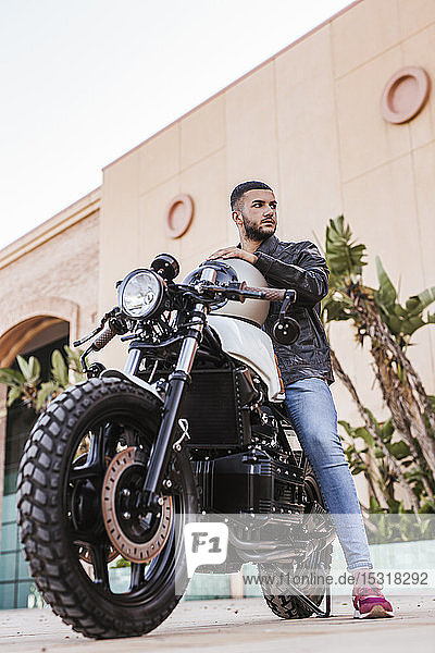 Porträt eines jungen Mannes  der auf seinem Motorrad sitzt