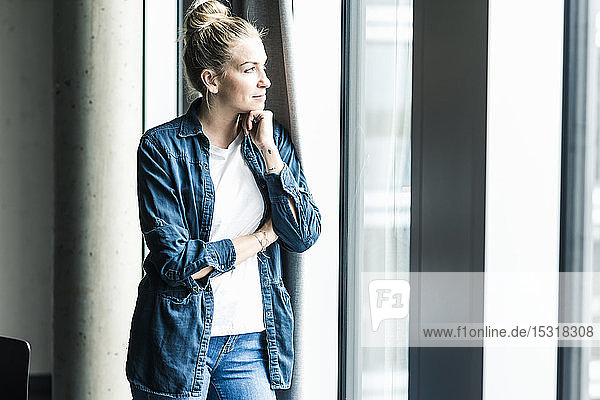 Businesswoman standing at the window in office looking out
