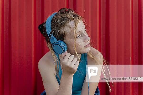 Mädchen mit Kopfhörern vor roter Wand