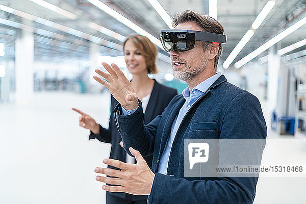 Geschäftsmann mit AR-Brille und Geschäftsfrau in einer Fabrikhalle