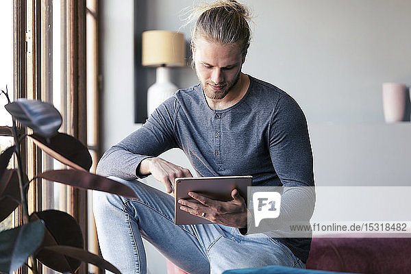 Junger Mann benutzt zu Hause ein digitales Tablett
