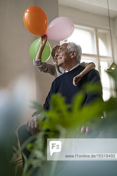 Glücklicher Großvater und Enkel  die zu Hause mit Luftballons spielen