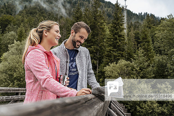 Glückliches junges Paar auf einer Wanderung beim Kartenlesen auf einer Holzbrücke  Vorderriss  Bayern  Deutschland