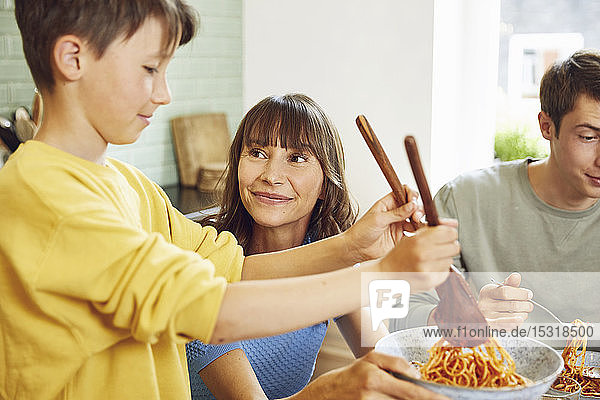 Mother eating spaghetti with her sons in the kitchen