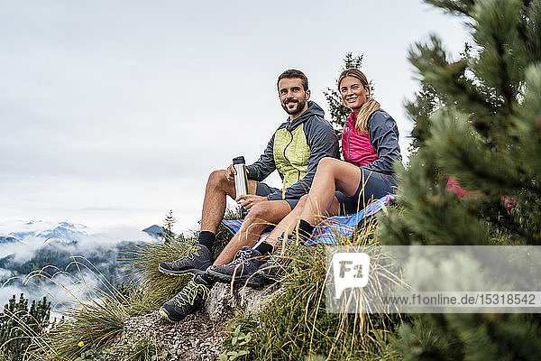 Young couple on a hiking trip in the mountains having a break  Herzogstand  Bavaria  Germany