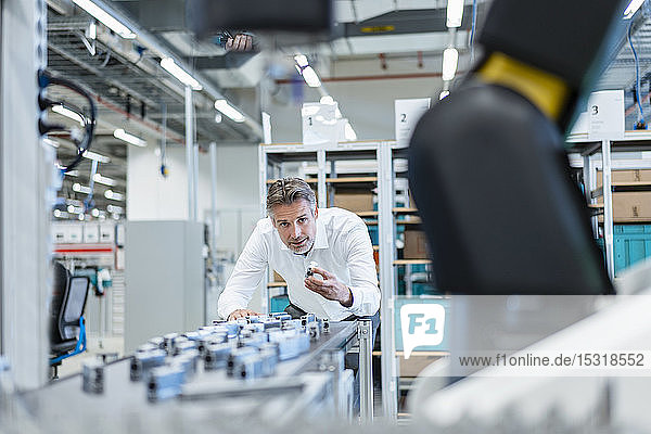 Businessman in a modern factory hall examiming workpieces