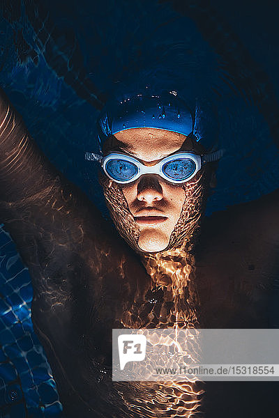 Porträt eines jungen paralympischen Schwimmers  der in einem Schwimmbecken auf dem Wasser schwimmt