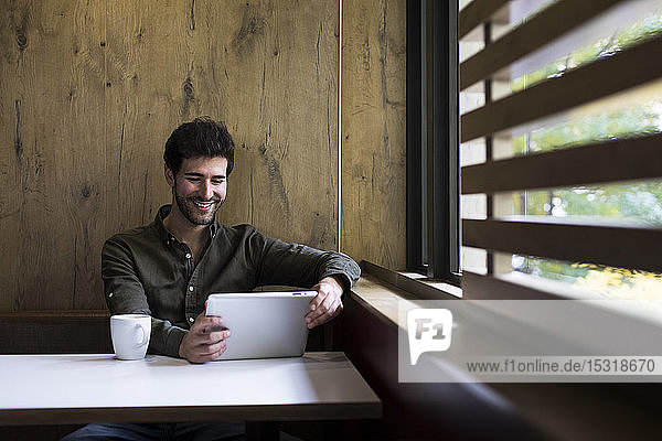 Porträt eines lächelnden Mannes mit digitalem Tablett in einem Cafe