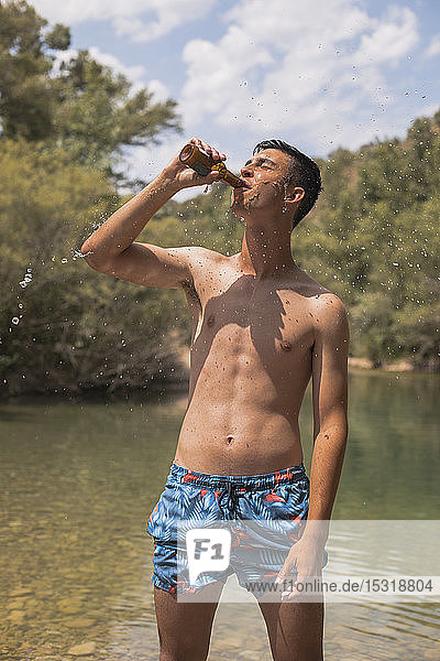 Junger Mann trinkt Bier an einem See  Spanien