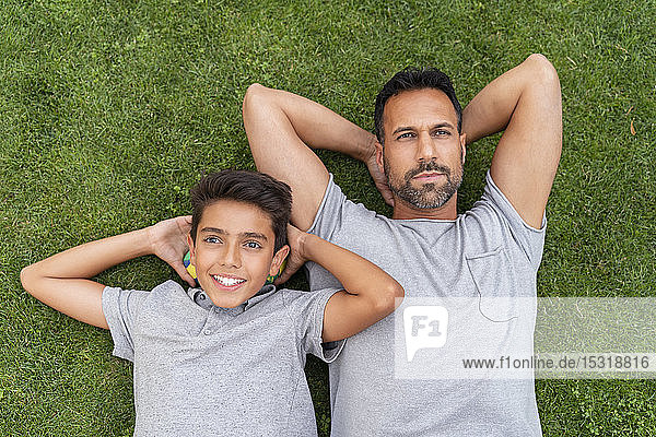 Vater und Sohn liegen zusammen im Gras