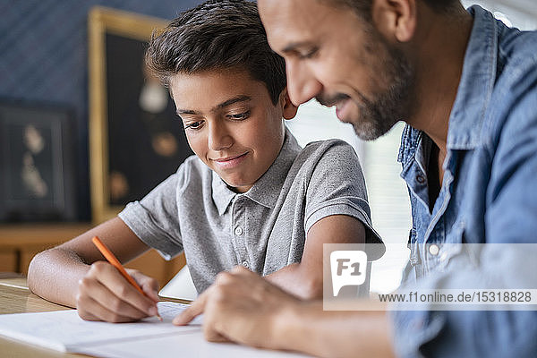 Lächelnder Vater hilft dem Sohn bei den Hausaufgaben