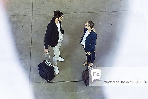 Zwei junge Geschäftspartner mit Gepäck im Gespräch