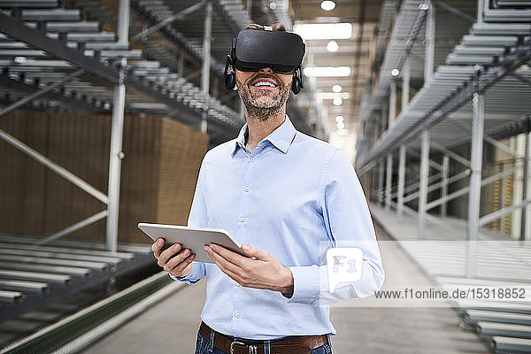 Geschäftsmann mit Tablette mit VR-Brille in der Fabrik