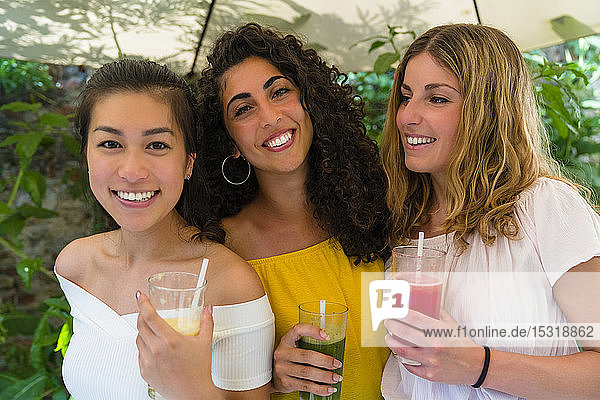 Porträt von drei glücklichen jungen Frauen mit gesunden Getränken