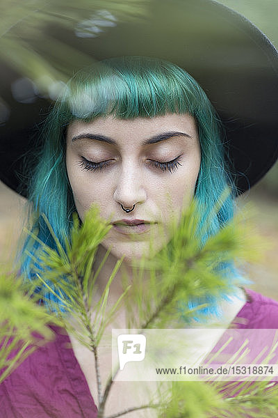Bildnis einer jungen Frau mit gefärbten blauen und grünen Haaren und Nasenpiercing in Natur