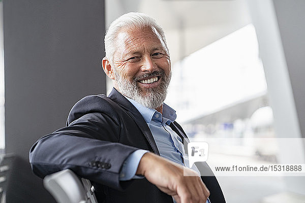 Porträt eines lächelnden reifen Geschäftsmannes  der im Wartebereich sitzt