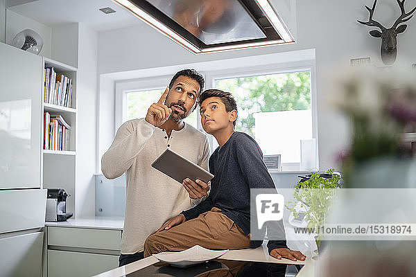 Vater und Sohn benutzen Tablette in der Küche
