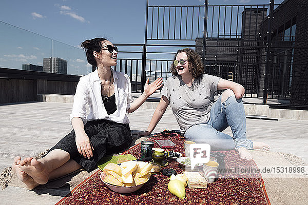 Frau mit Unterarmamputation mit ihrer Freundin beim gesunden Essen auf dem Dach