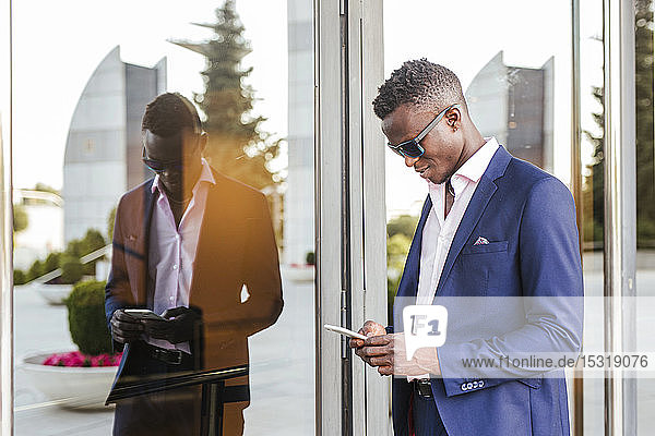 Young businessman using his smartphone outside