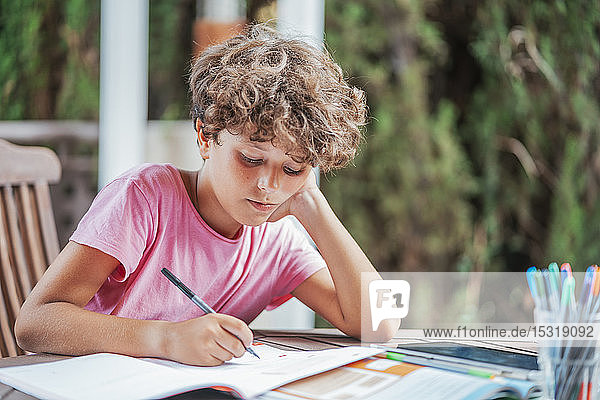 Boy sitting at garden table doing homework