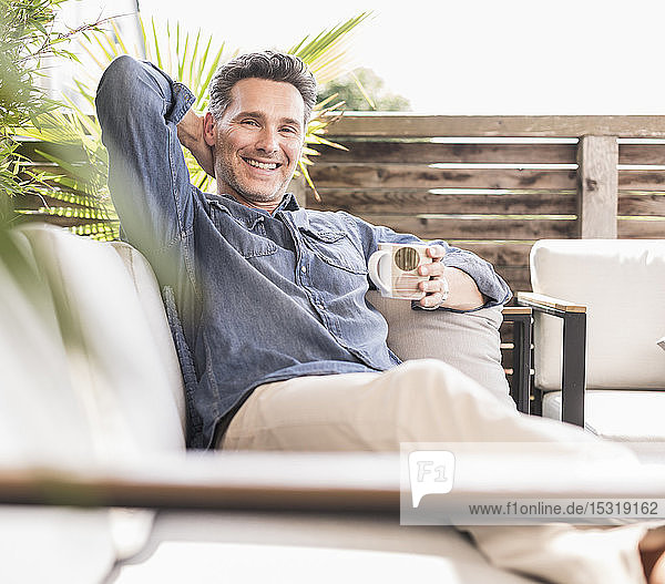 Confident man relaxing on the terrace drinking coffee