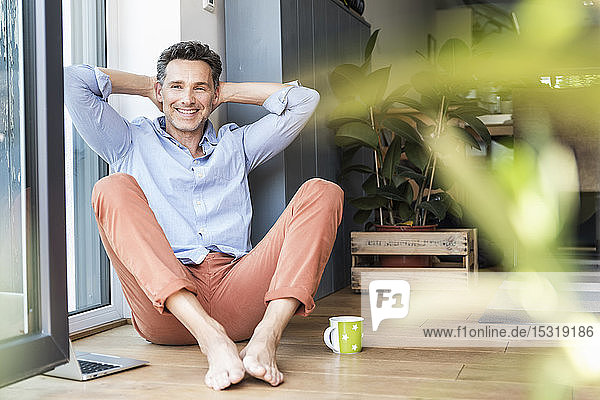 Mature man relaxing at home with a cup of coffee using laptop