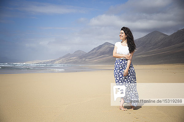 Glückliche Frau steht am Strand und schaut in die Ferne  Fuerteventura  Spanien