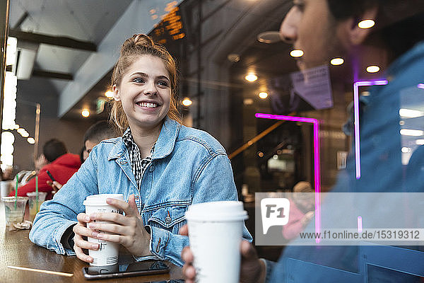 Porträt einer lächelnden jungen Frau in einem Café  die einen jungen Mann ansieht