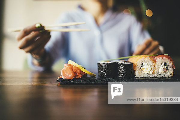 Close-up of a woman eating sushi in a restaurant