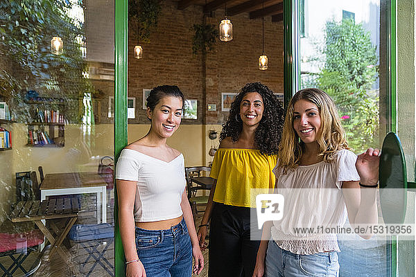 Porträt von drei lächelnden jungen Frauen in einem Cafe