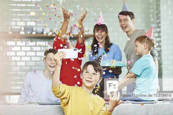Mutter und Söhne feiern Großmutters Geburtstag in ihrer Küche  Junge nimmt sich selbst