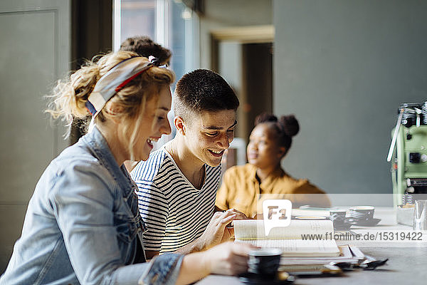 Schülerinnen und Schüler treffen sich im Café  lernen gemeinsam  mit Laptop und Smartphones