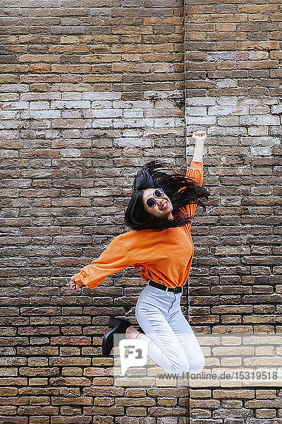 Asian woman jumping  brick wall in the background