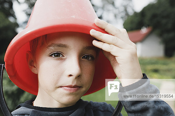 Bildnis eines Jungen mit einem roten Eimer auf dem Kopf