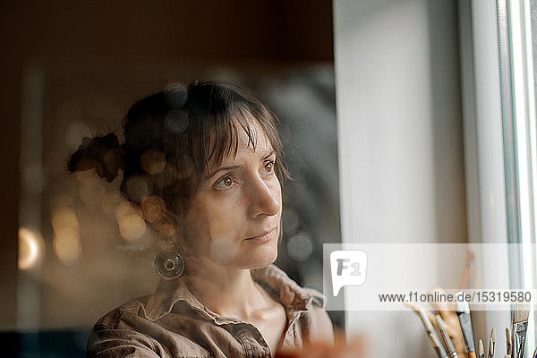 Porträt einer Künstlerin in ihrem Atelier mit Blick aus dem Fenster
