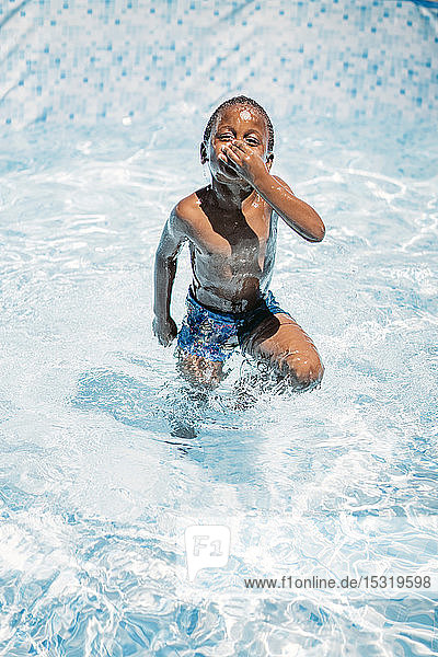 Afrikanisches Kind amüsiert sich im Schwimmbad  hält sich die Nase zu