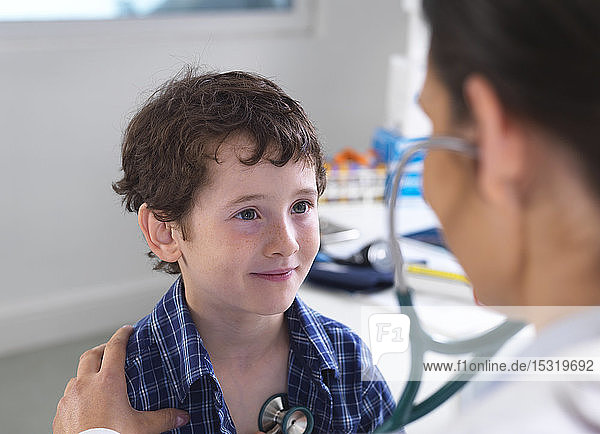 Female doctor examiming a boy using a stethoscope
