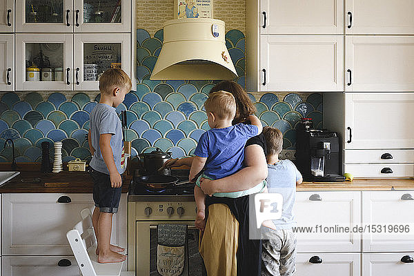 Mutter kocht mit ihren drei Söhnen in der Küche