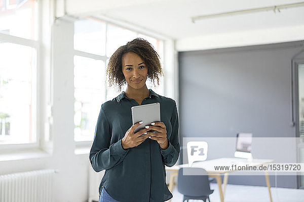 Porträt einer lächelnden jungen Geschäftsfrau mit digitalem Tablet im Büro